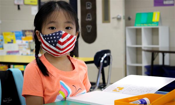 girl smiles while wearing mask